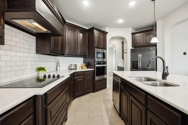 a kitchen with stainless steel appliances granite countertop a sink refrigerator and cabinets