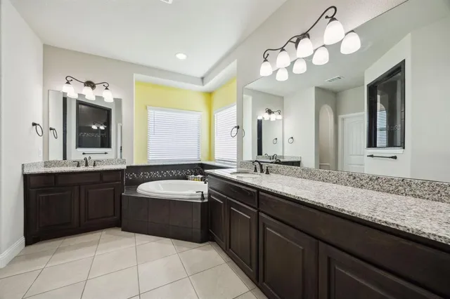 a bathroom with a granite countertop double vanity sink and a mirror