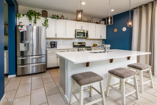 a kitchen with stainless steel appliances a refrigerator a stove a sink cabinets and a dining table