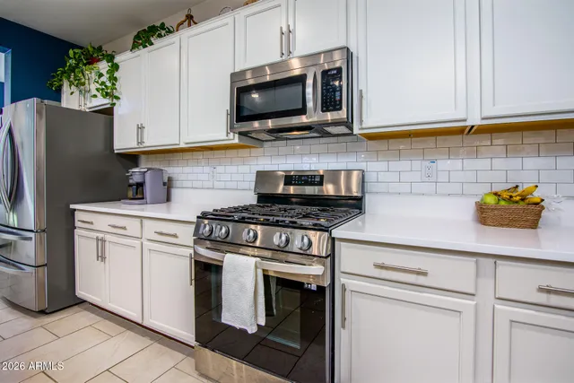 a kitchen with stainless steel appliances granite countertop white cabinets a stove a microwave and a refrigerator