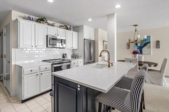 66 Glades Road, Unit 5 Scituate, MA 02066 - Photo 2 of 11 a kitchen with a sink a kitchen island and stainless steel appliances