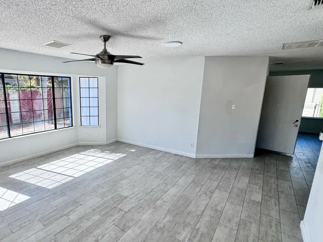 a view of an empty room with a window and wooden floor