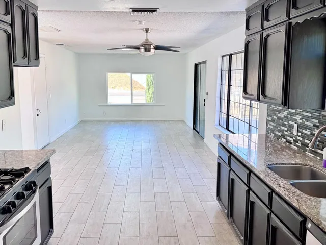 a kitchen with granite countertop a sink stove and cabinets