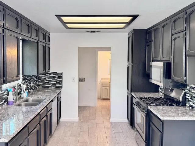 a kitchen with stainless steel appliances granite countertop a sink stove and refrigerator