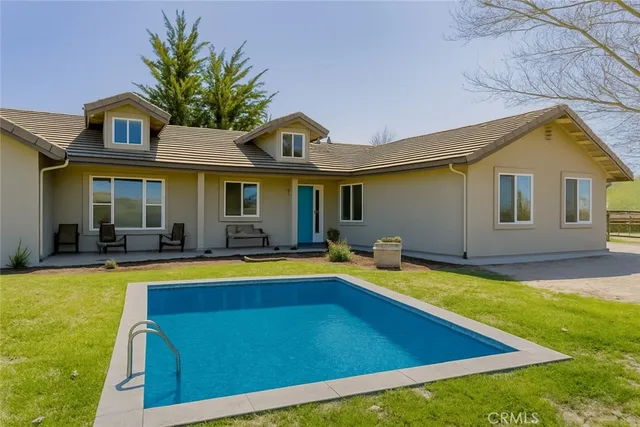 a view of swimming pool with lawn chairs and plants