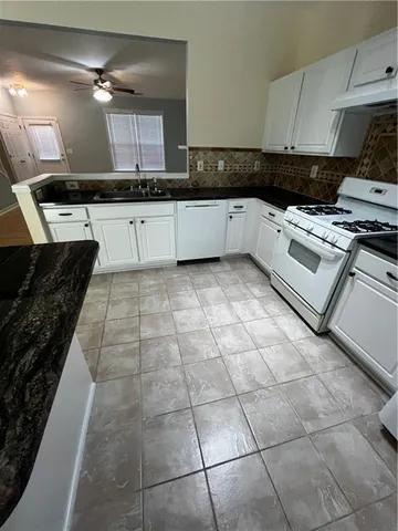 a kitchen with granite countertop a stove a sink and a counter top space