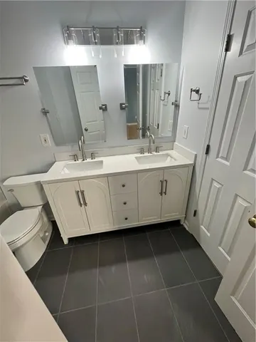 a spacious bathroom with a double vanity sink a mirror and a toilet