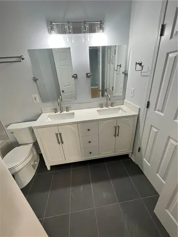 a spacious bathroom with a double vanity sink a toilet and a mirror
