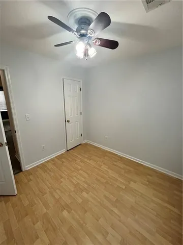 an empty room with a chandelier fan and wooden floor