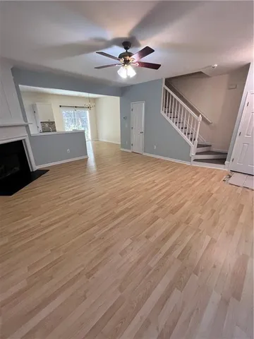 a view of an empty room with wooden floor and a ceiling fan