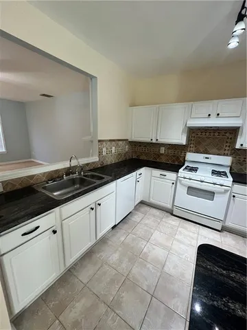 a kitchen with granite countertop a sink a stove and cabinets
