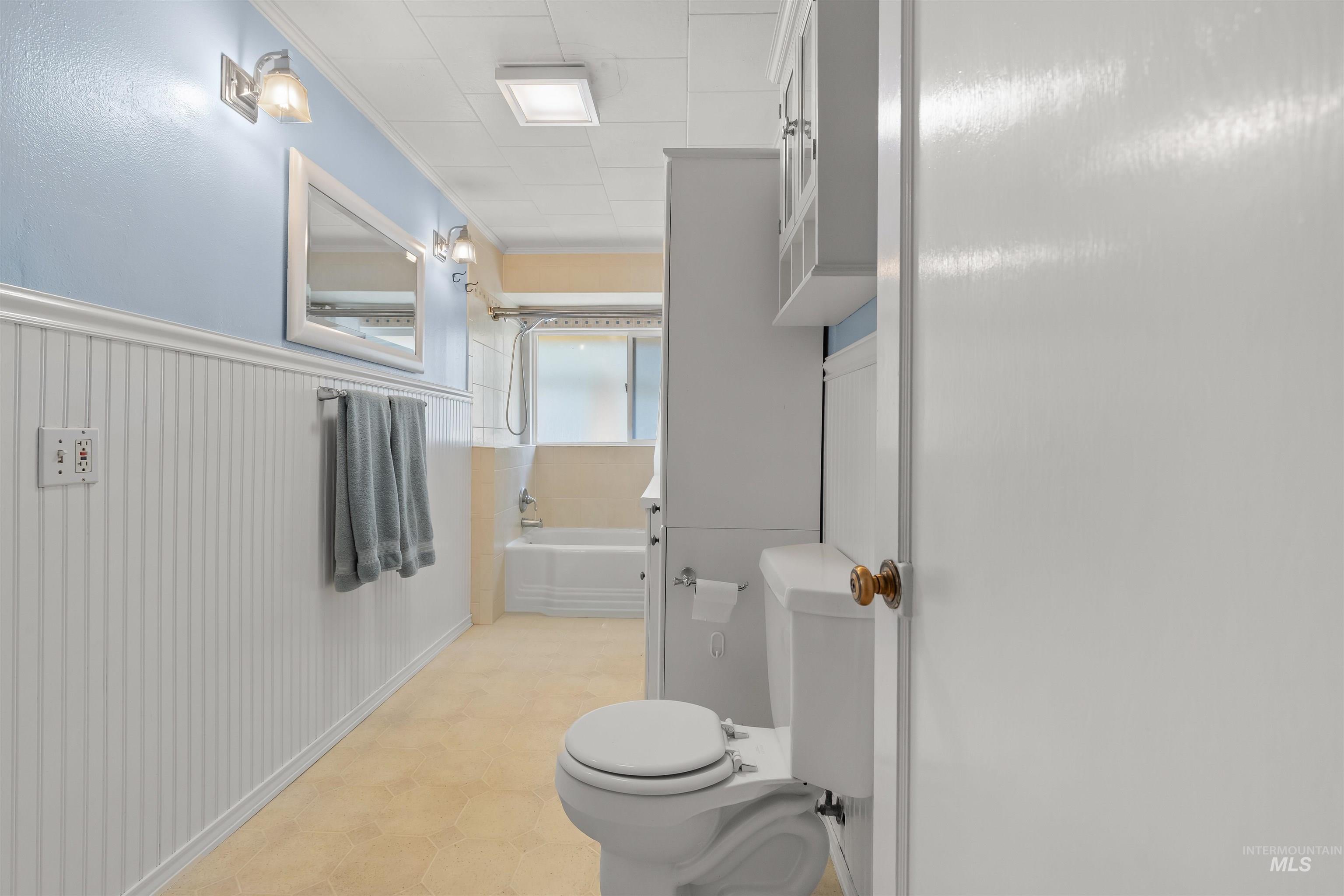 619 Prospect Avenue Lewiston, ID 83501 - Photo 20 of 37 Bathroom featuring a full-size bathtub, vanity mirror, wall-mounted light fixtures, beadboard wainscoting, and a built-in storage cabinet