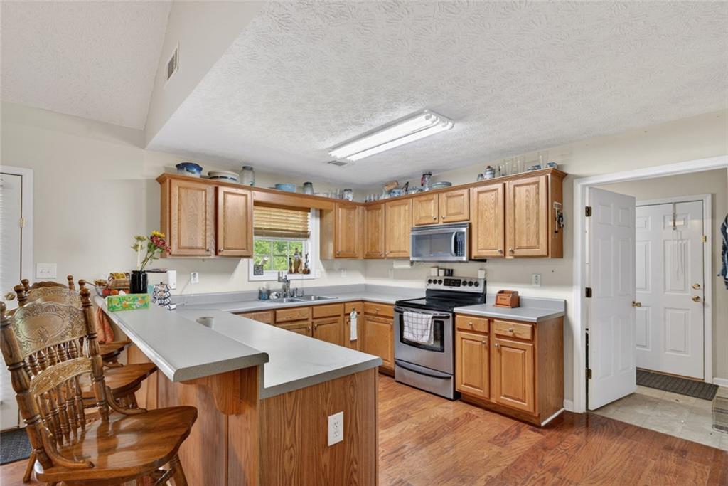 120 Norman Road Covington, GA 30014 - Photo 7 of 31 a kitchen with a stove sink cabinets and wooden floor