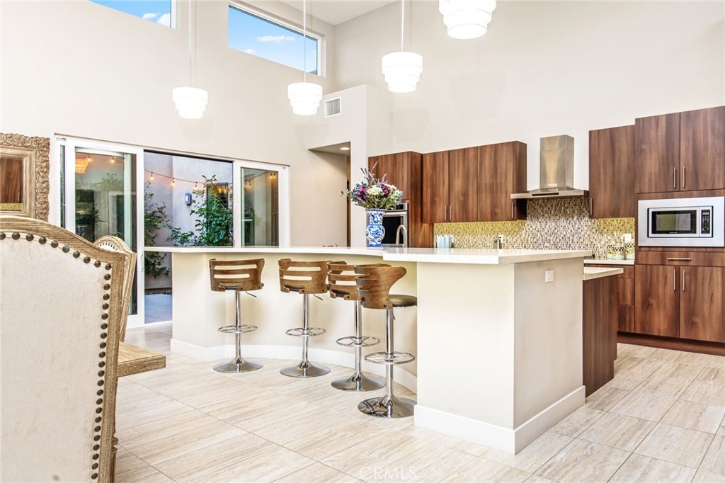 15 Via Montagna Rancho Mirage, CA 92270 - Photo 29 of 75 a kitchen with stainless steel appliances kitchen island granite countertop a refrigerator a stove a microwave oven with white cabinets and wooden floor