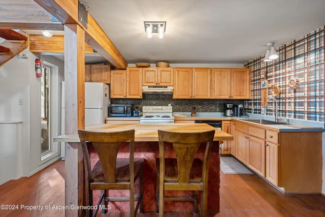 a kitchen with stainless steel appliances granite countertop a table chairs sink and wooden cabinets