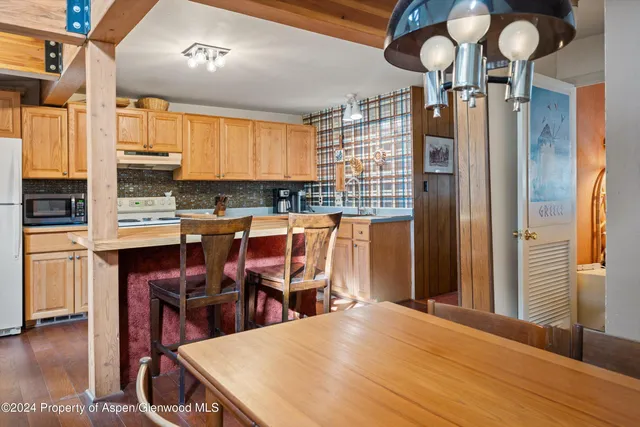 a kitchen with stainless steel appliances kitchen island granite countertop a table chairs in it and wooden floors