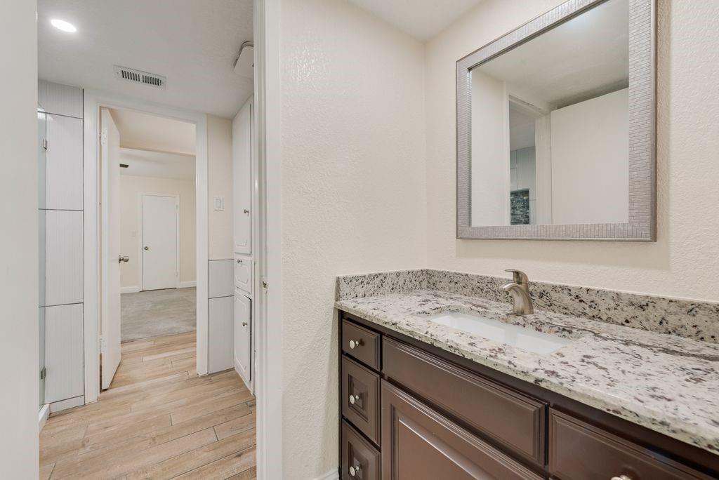 219 West Rochelle Road Irving, TX 75062 - Photo 24 of 29 Bathroom vanity featuring a speckled countertop, undermount sink, and dark wood cabinetry with brushed nickel hardware