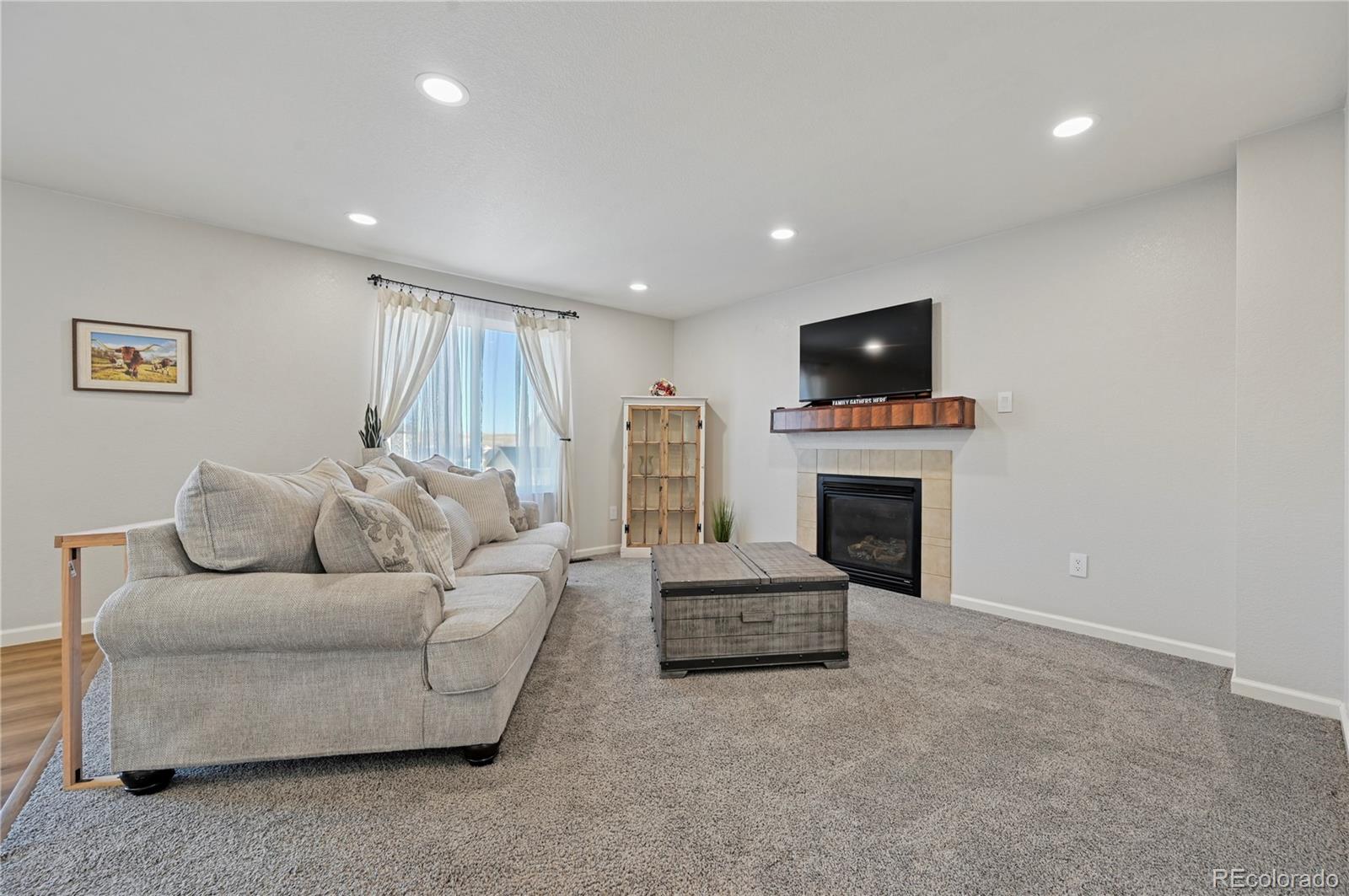 795 Winebrook Way Fountain, CO 80817 - Photo 12 of 41 a living room with furniture a fireplace and a flat screen tv