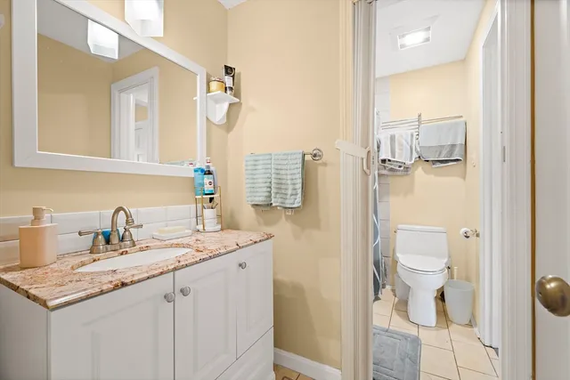 a bathroom with a granite countertop sink a toilet and a mirror