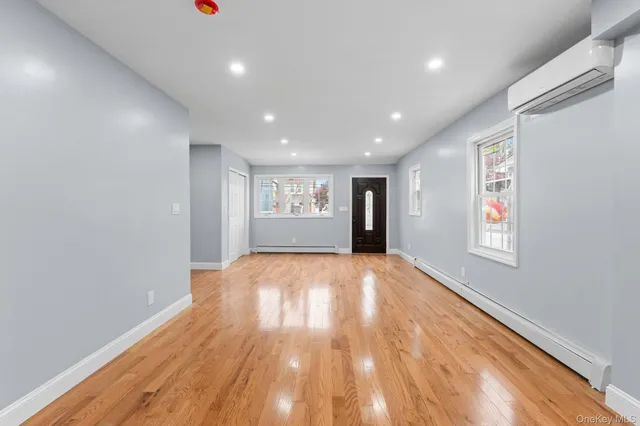 a view of an empty room with wooden floor and windows