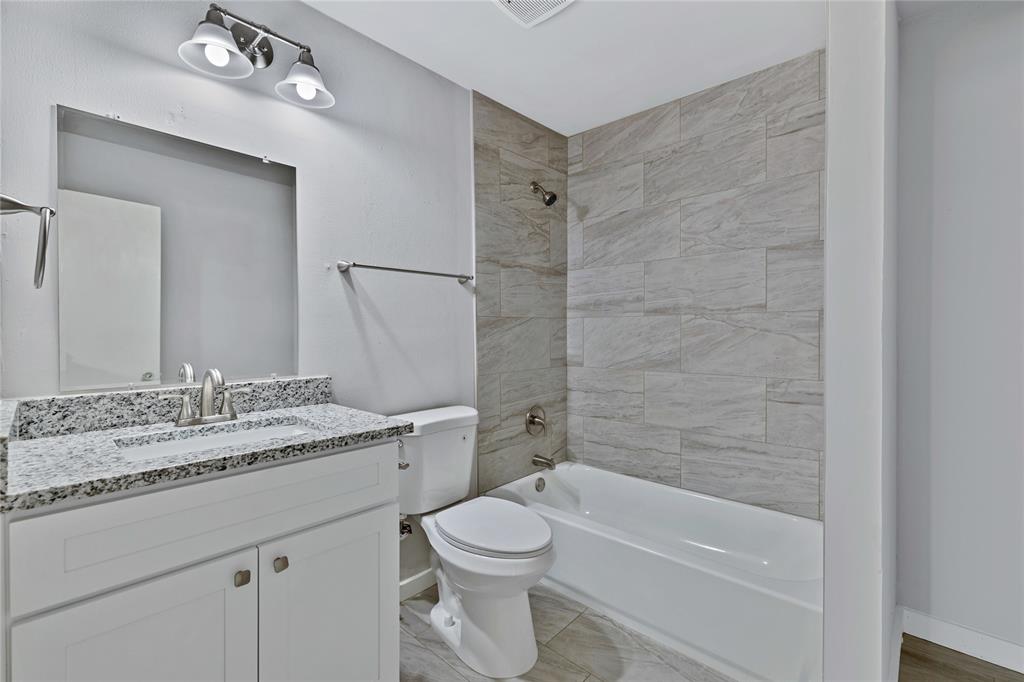 907 Southwest Main Street Ennis, TX 75119 - Photo 11 of 28 a bathroom with a granite countertop sink a toilet and shower