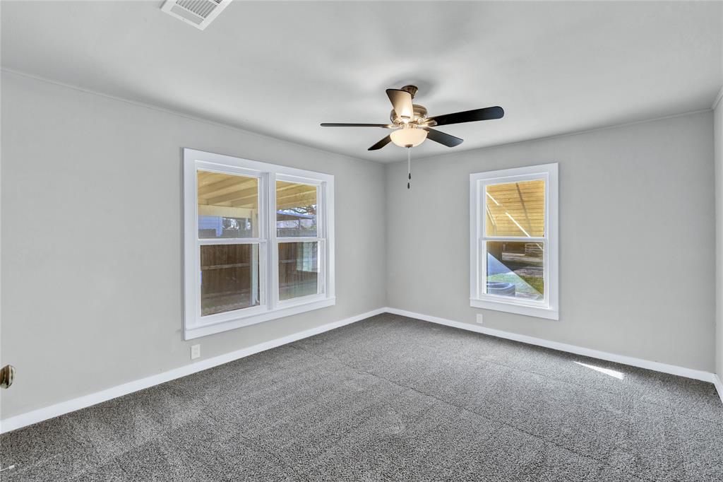 907 Southwest Main Street Ennis, TX 75119 - Photo 12 of 28 an empty room with windows and ceiling fan