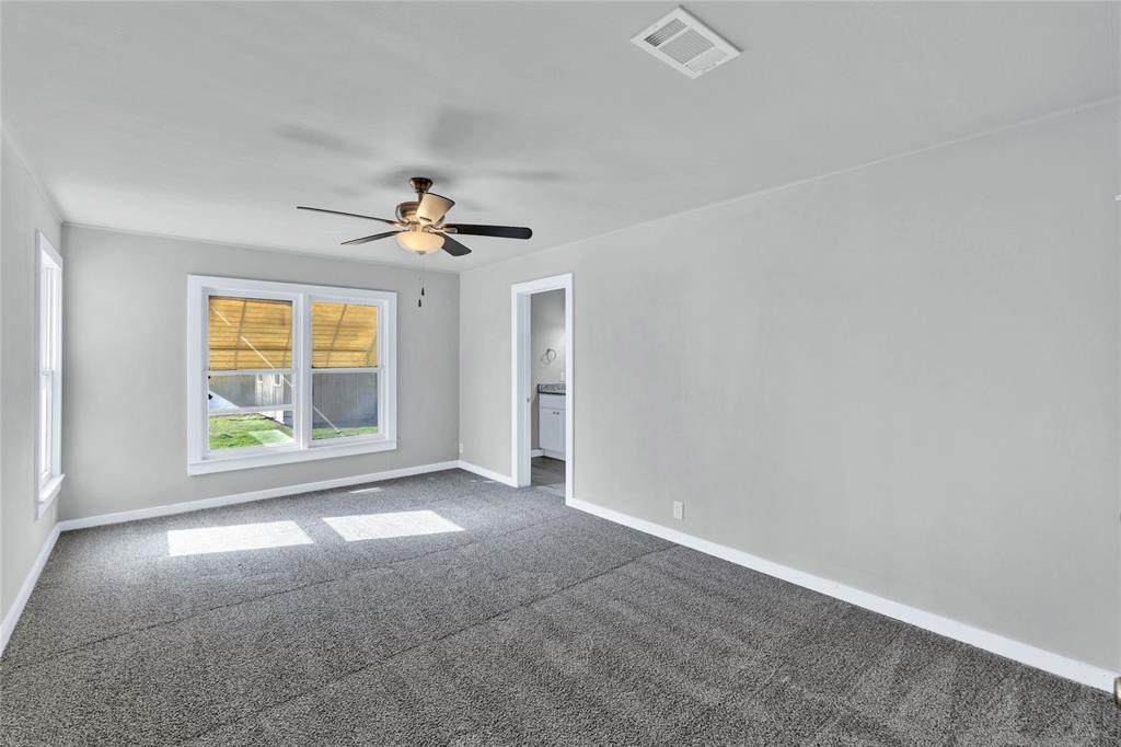 907 Southwest Main Street Ennis, TX 75119 - Photo 14 of 28 an empty room with windows and a ceiling fan