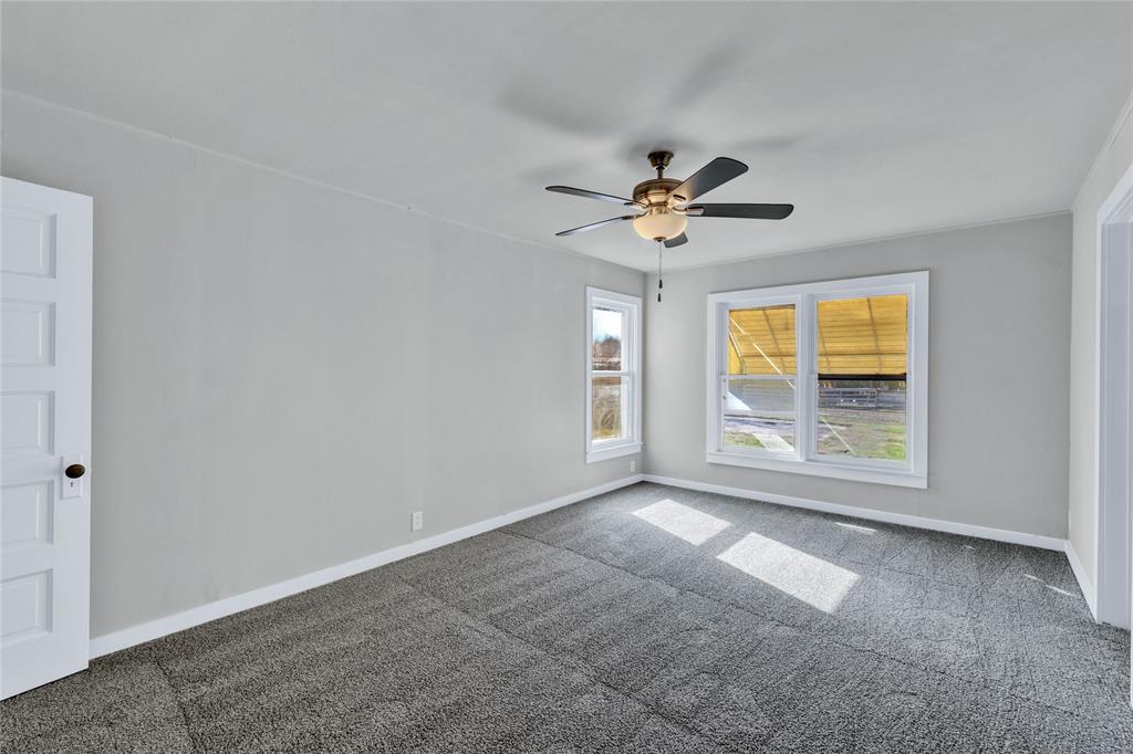 907 Southwest Main Street Ennis, TX 75119 - Photo 15 of 28 an empty room with windows and ceiling fan