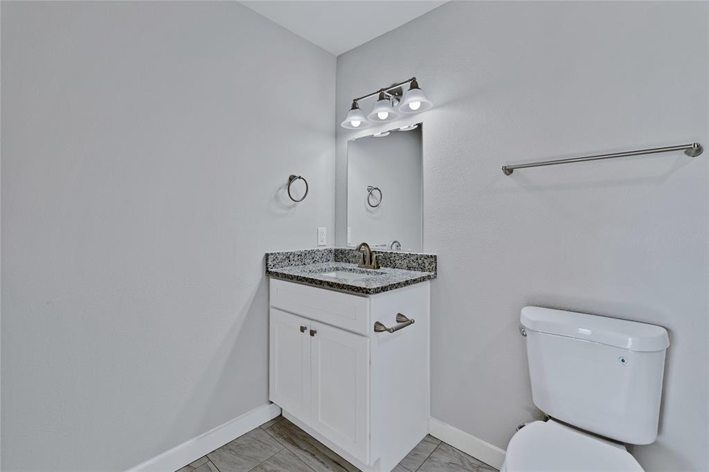 907 Southwest Main Street Ennis, TX 75119 - Photo 17 of 28 a bathroom with a toilet sink and mirror