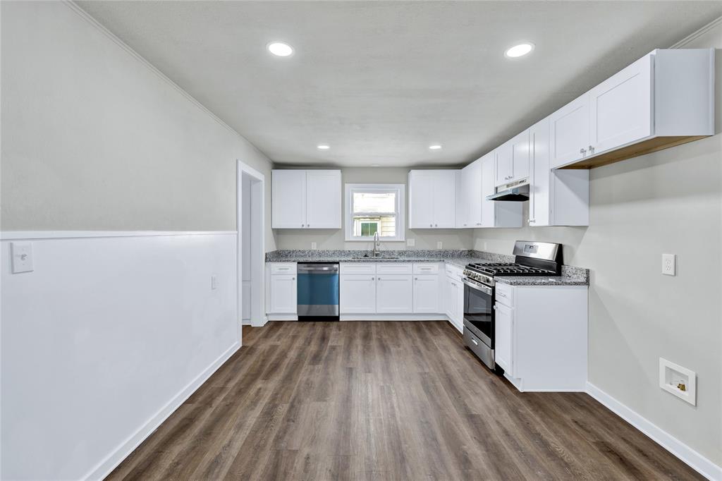 907 Southwest Main Street Ennis, TX 75119 - Photo 5 of 28 a kitchen with wooden floors and white appliances