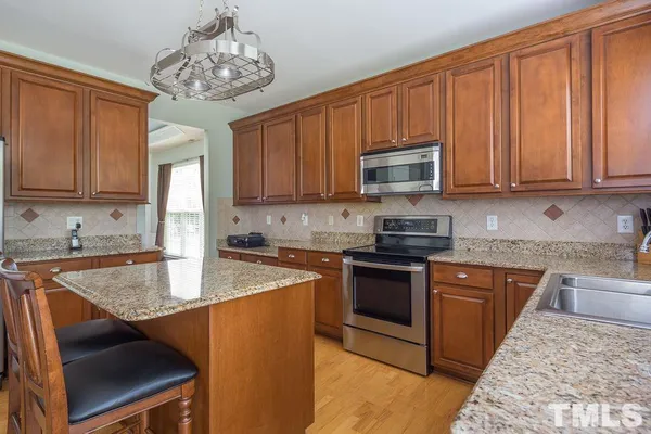 a kitchen with stainless steel appliances granite countertop a stove top oven a sink dishwasher and cabinets with wooden floor
