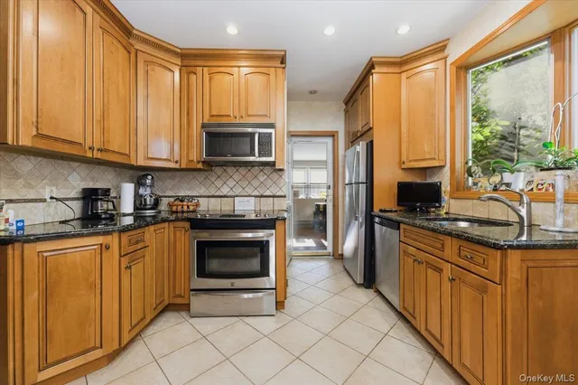 a kitchen with stainless steel appliances granite countertop a stove top oven a sink a counter space and cabinets