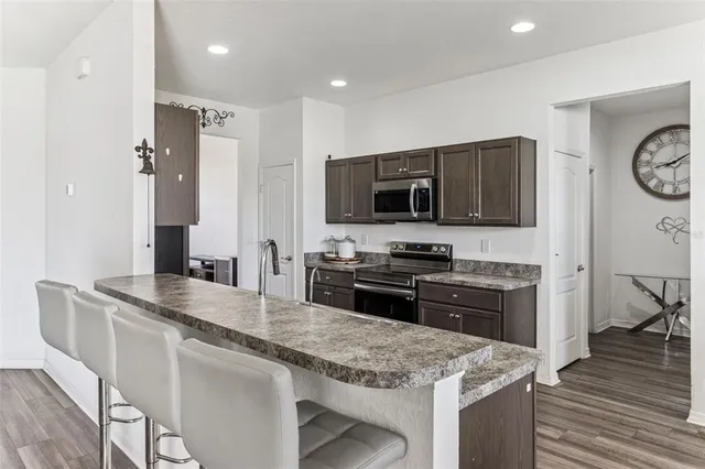 a kitchen with stainless steel appliances granite countertop a sink stove microwave and refrigerator