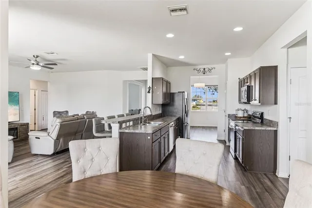 a living room with stainless steel appliances kitchen island granite countertop a couch and wooden floor