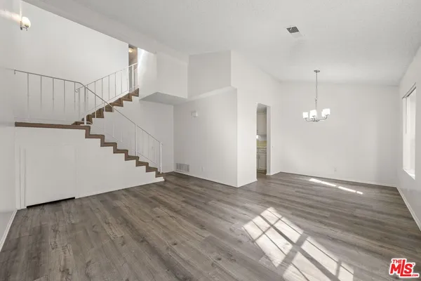 a view of an empty room with wooden floor and stairs
