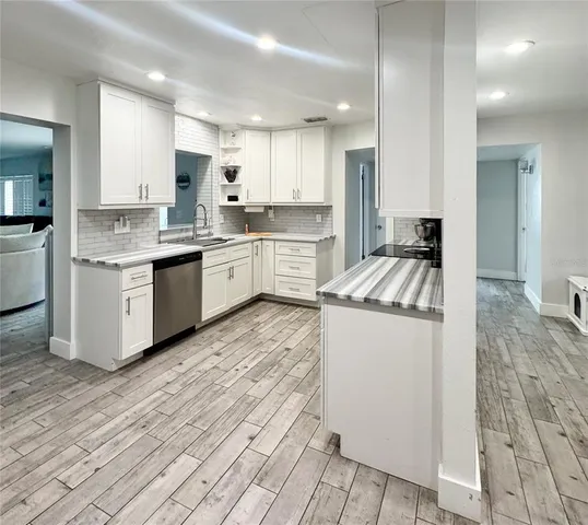 a kitchen with granite countertop a sink and white cabinets
