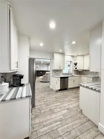 a kitchen with a sink a stove a refrigerator and white cabinets