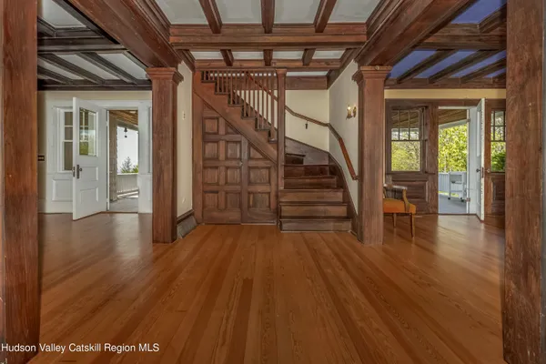a view of an empty room with wooden floor fireplace and a window
