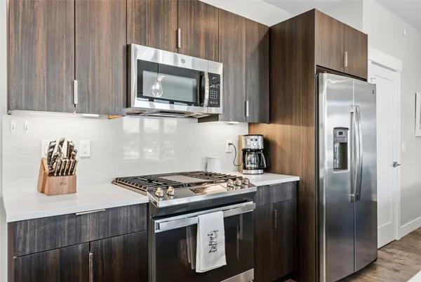 a kitchen with stainless steel appliances granite countertop a stove a refrigerator and a microwave
