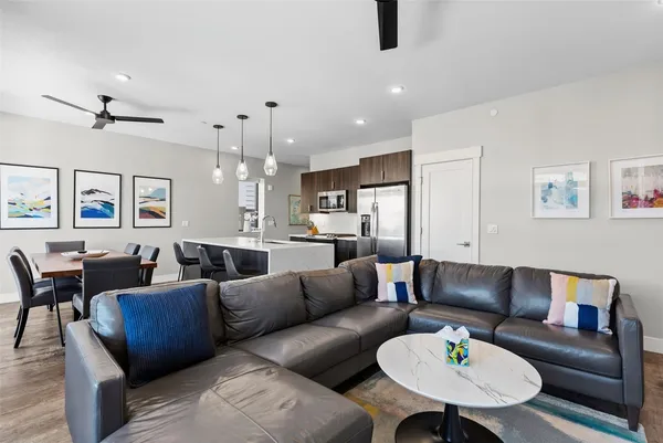 a living room with furniture kitchen view and a chandelier