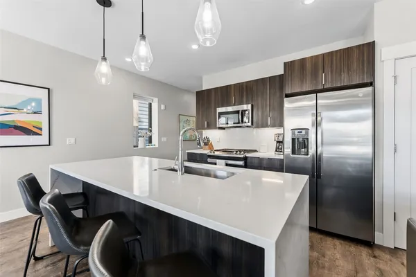 a kitchen with kitchen island a table chairs refrigerator and microwave