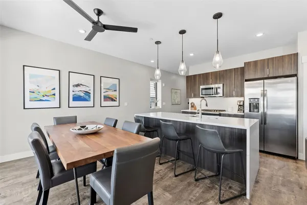 a kitchen with stainless steel appliances granite countertop a dining table chairs refrigerator and microwave