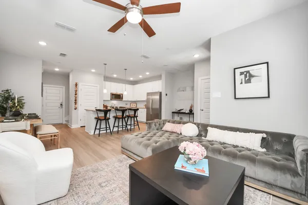 a living room with furniture and kitchen view with wooden floor