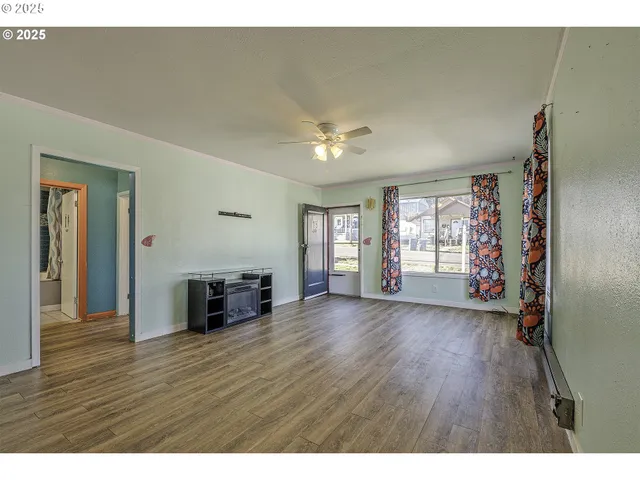 a view of an empty room with a window and wooden floor