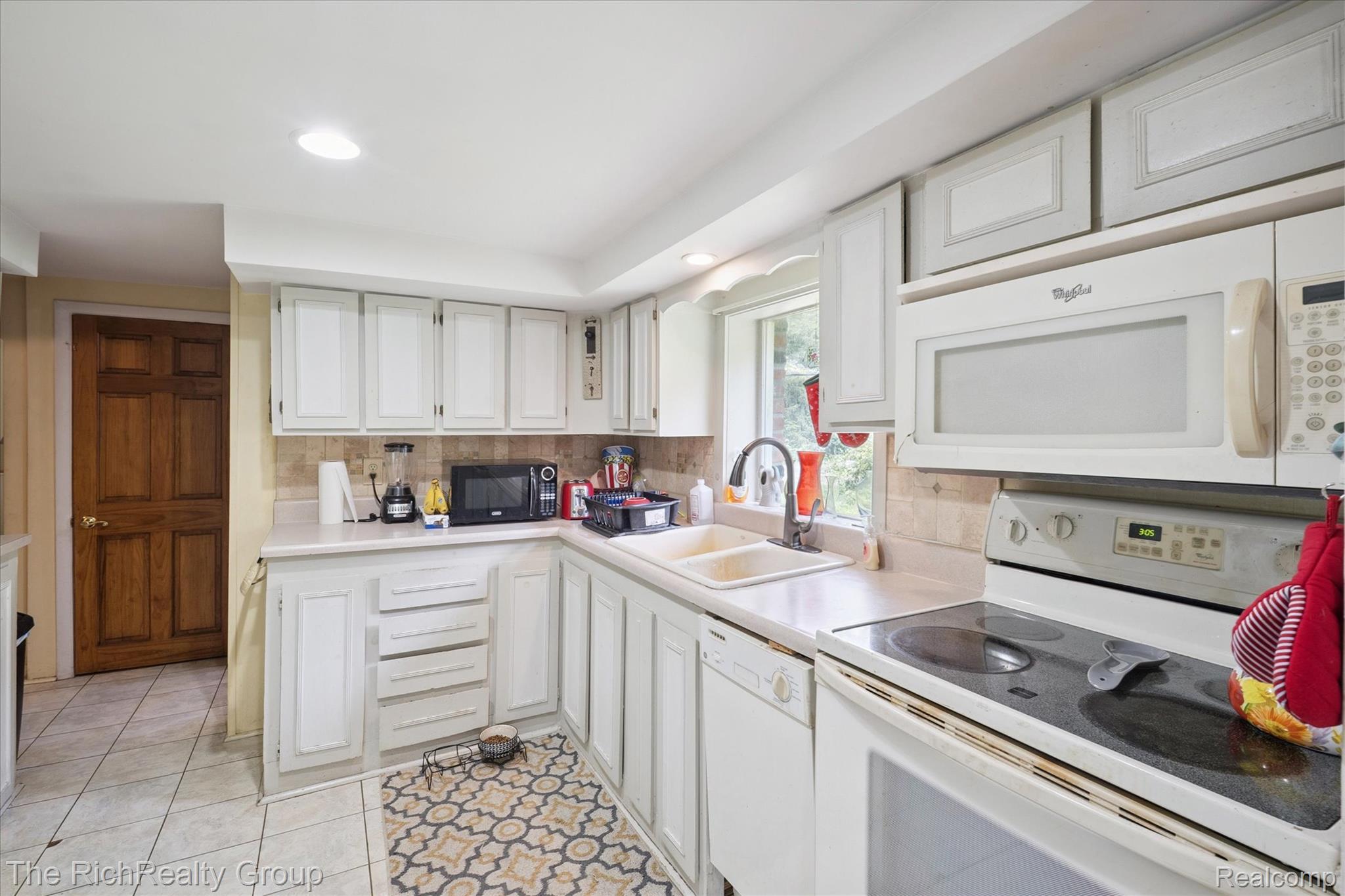 39635 Lotzford Road Canton, MI 48187 - Photo 23 of 39 Kitchen featuring white appliances, decorative backsplash, light countertops, light tile patterned flooring, and white cabinetry
