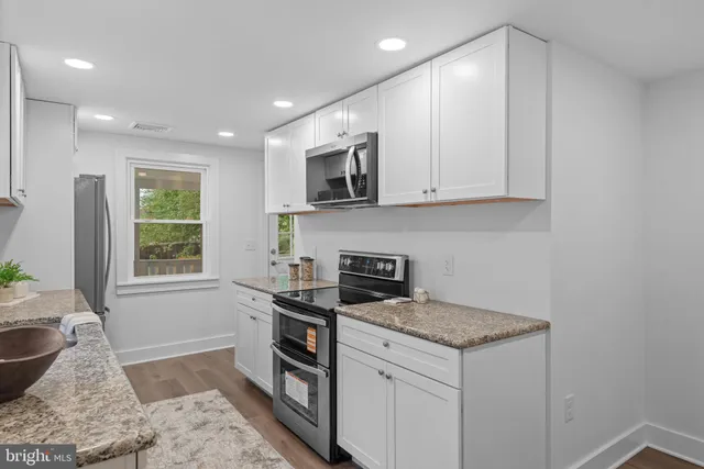 a kitchen with stainless steel appliances granite countertop a stove a sink and a microwave