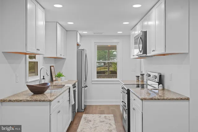 a kitchen with granite countertop a sink a stove and cabinets