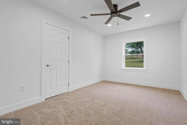 an empty room with a window and a fan