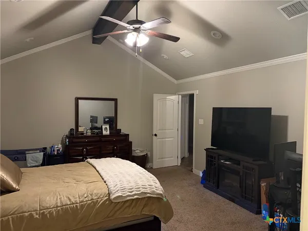a bedroom with a bed and a flat tv screen on a dresser
