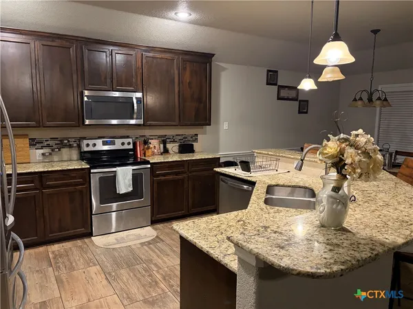 a kitchen with kitchen island granite countertop a sink counter top space appliances and cabinets